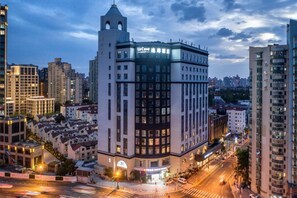 Um hotel de vários andares com localização de destaque na esquina, com entrada ampla e um restaurante visível.