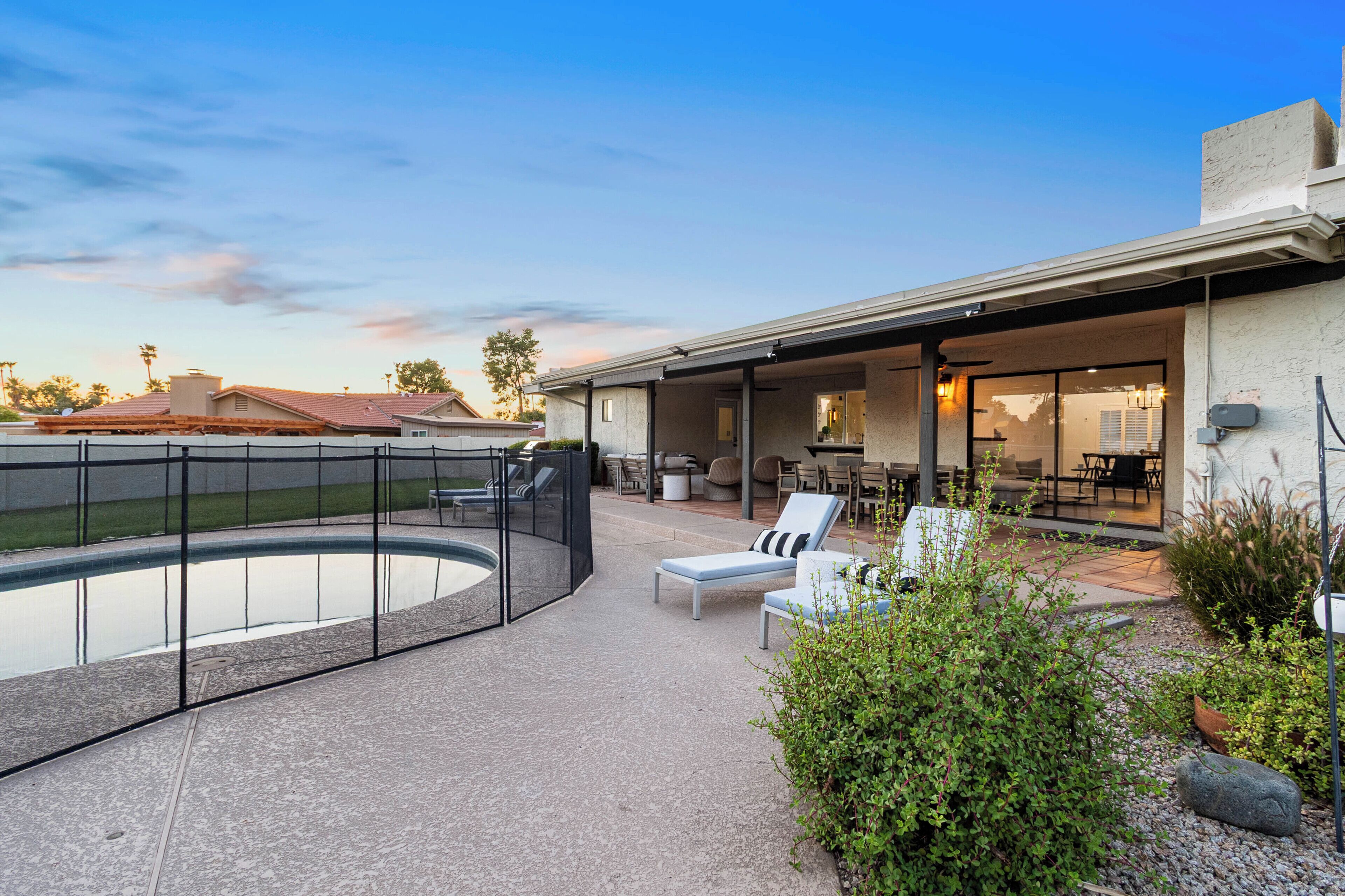A modern outdoor patio with a swimming pool, lounge chairs, and a covered dining area.