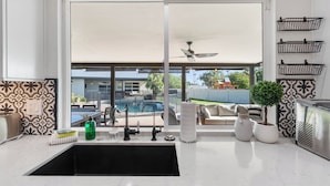 Cozinha com uma janela grande, um ventilador de teto e vista para uma piscina.