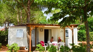 A small cabin with a porch, two chairs, and a table. - Bessan Mobile Home With Pool Fun (Bessan)