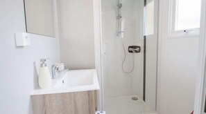 Un bagno moderno con lavandino bianco, specchio e cabina doccia in vetro.