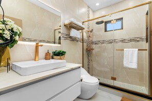 A modern bathroom with a glass-enclosed shower, a white sink, and a large mirror.