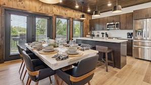 Eine moderne Küche mit Holzschränken, Edelstahlgeräten und einer großen Kochinsel mit Sitzgelegenheiten.