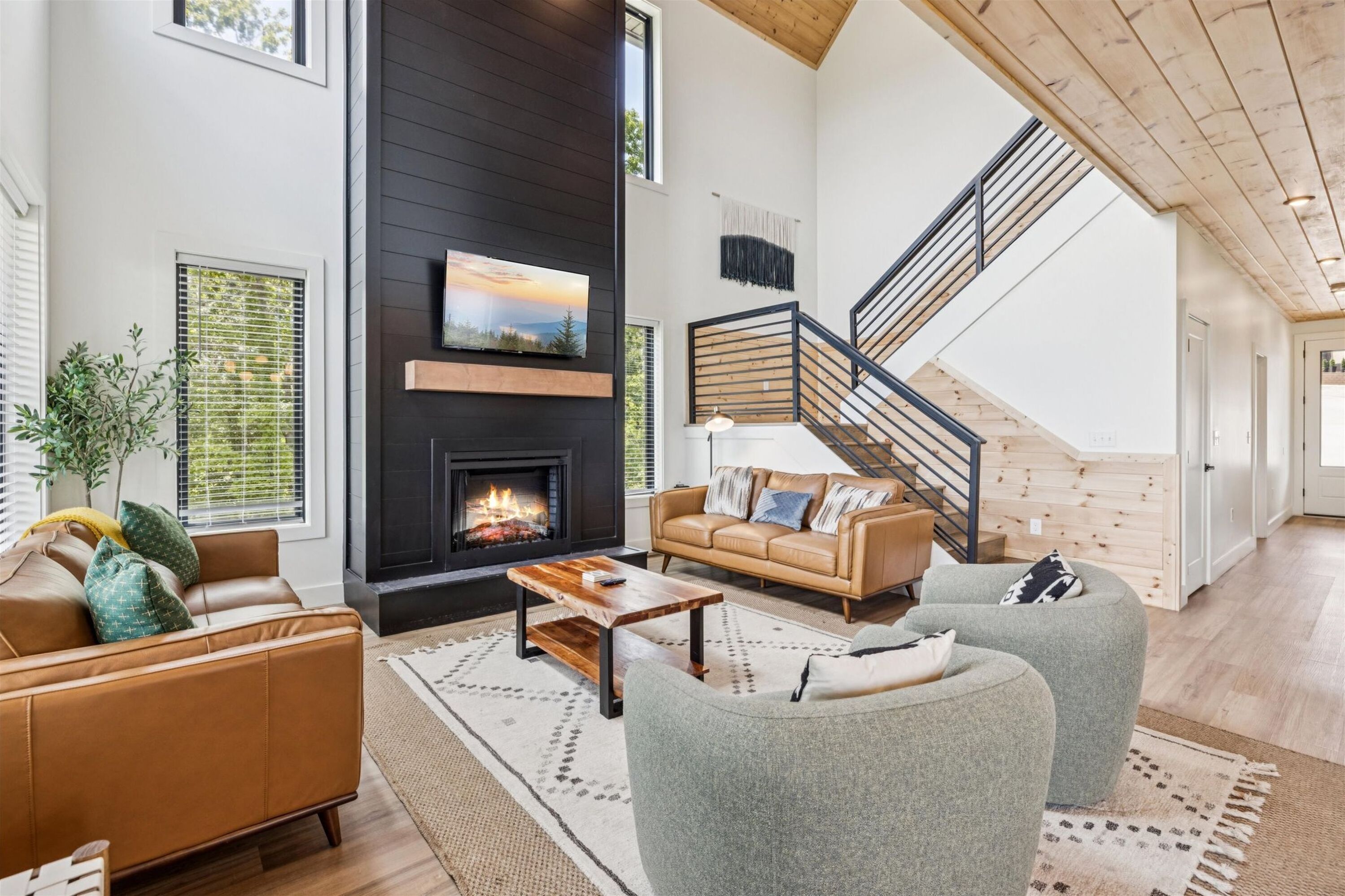 A spacious living room with a fireplace, a sofa, a coffee table, and a staircase leading to another level.