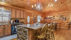 A wooden cabin interior with a kitchen, dining area, and bar seating.