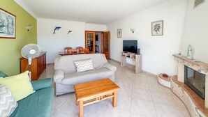 Ein Wohnzimmer mit einer Couch, einem Holztisch, einem Fernseher und einem Kamin.