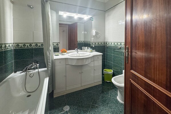 A bathroom with a bathtub, sink, and toilet. - Wake up to ocean views and step into Old Town charm. (Albufeira)