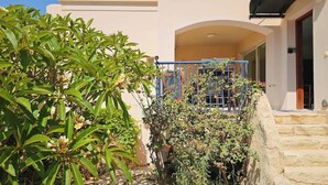 A courtyard with a stone staircase, a blue railing, and lush greenery.