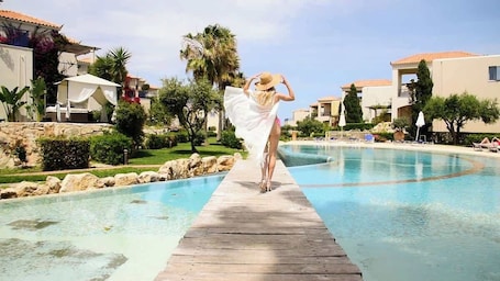 Una piscina al aire libre, sombrillas, sillones reclinables de piscina