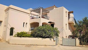 A two-story building with balconies, a covered outdoor seating area, and a small garden.
