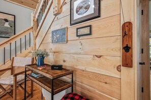 Ein Holzinterieur mit einer Treppe, einem Tisch mit Lautsprecher und gerahmten Kunstwerken an der Wand.