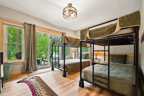 Una habitación con literas, un ventanal con cortinas, suelo de madera y ventilador de techo.