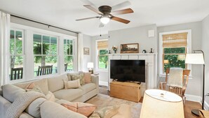 A living room with a sofa, TV, fireplace, and large windows.