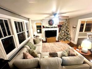 A living room with a sofa, a television, a fireplace, and a Christmas tree.
