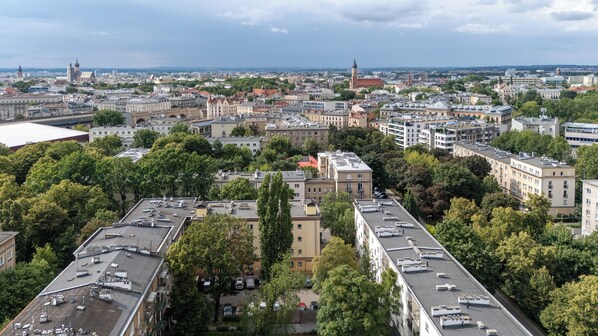 An aerial view of a cityscape with various buildings, including a prominent tower and several residential areas with trees.
