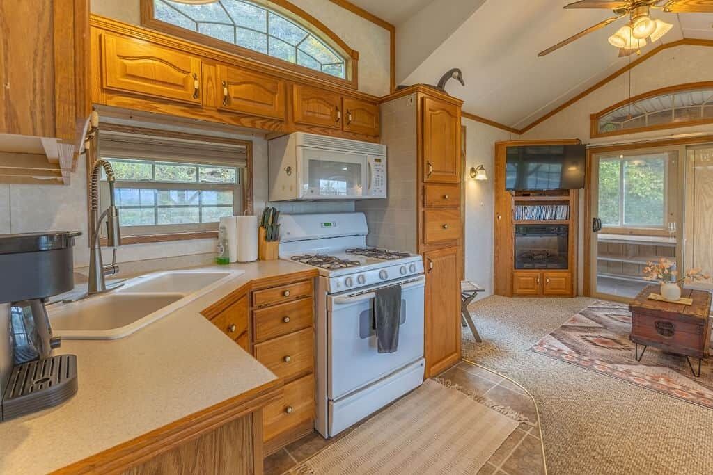 Une cuisine avec des meubles de rangement en bois, une cuisinière, un four à micro-ondes et un évier.