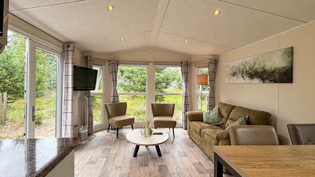 A spacious living area with a large window, a flat-screen TV, and a comfortable seating arrangement.