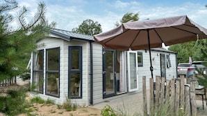 A small, single-story cabin with large windows and a covered patio area.