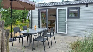 An outdoor patio with a table and chairs, a bottle, and a glass.