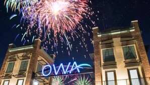 Un bâtiment sur lequel on peut lire l’inscription « OWA », avec des feux d’artifice en arrière-plan.