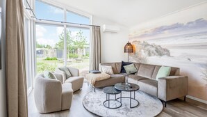 Un salon comprenant un ensemble de canapés, une table basse et une vue sur l’extérieur grâce à de grandes fenêtres.