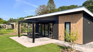 Un bâtiment moderne doté d’un patio couvert, de grandes fenêtres et d’une pelouse bien entretenue.