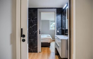 A modern bedroom with a bed, a small window, and a bathroom with a mirror and sink. - Awesome home in Voorthuizen (Voorthuizen)