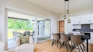 A modern kitchen with white cabinets, a black countertop, and a dining area with a table and chairs. - Awesome home in Voorthuizen (Voorthuizen)