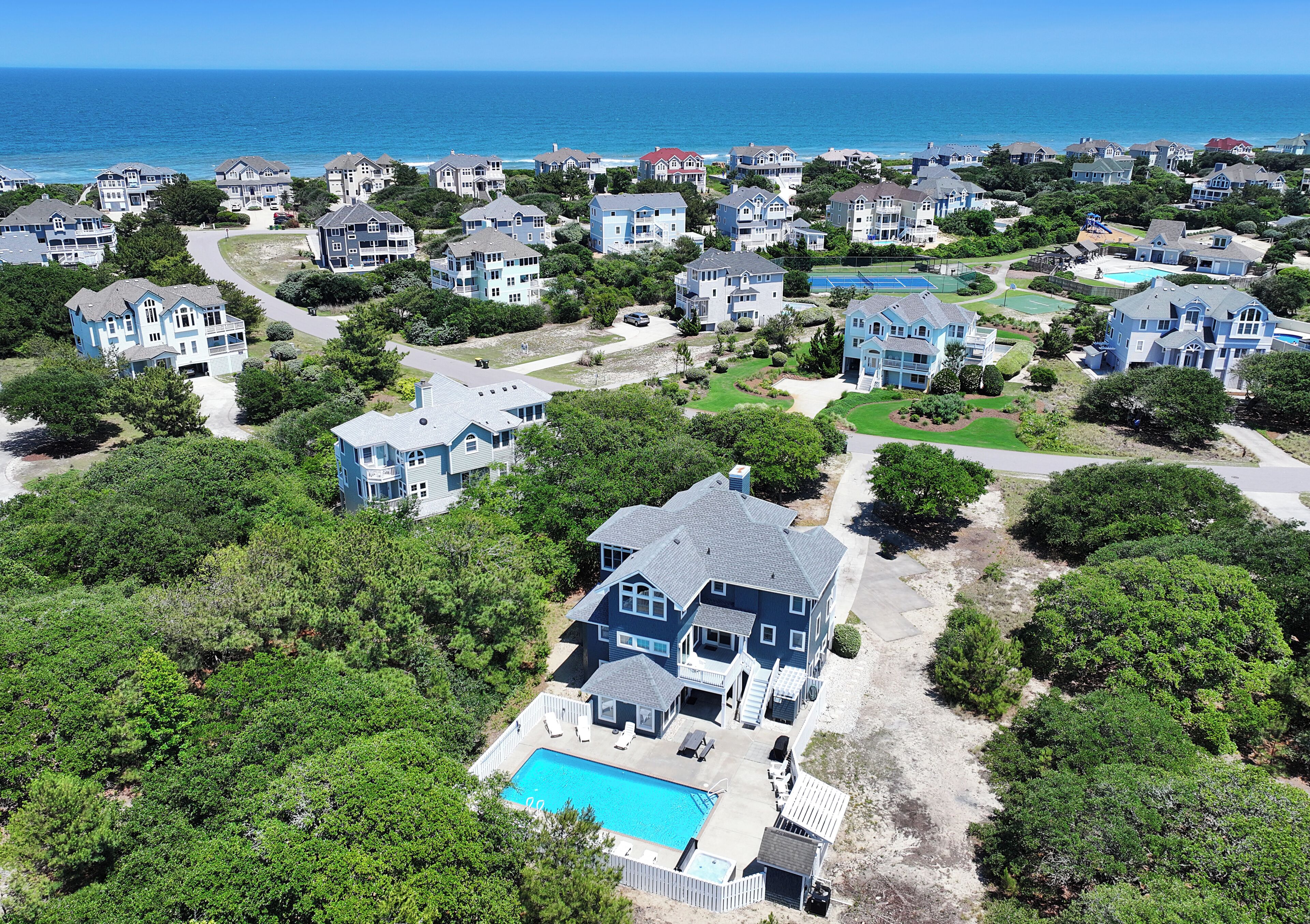 A residential area with houses, a swimming pool, and a view of the ocean.