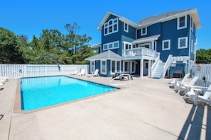 A two-story house with a swimming pool, a covered patio, and a fenced deck area.