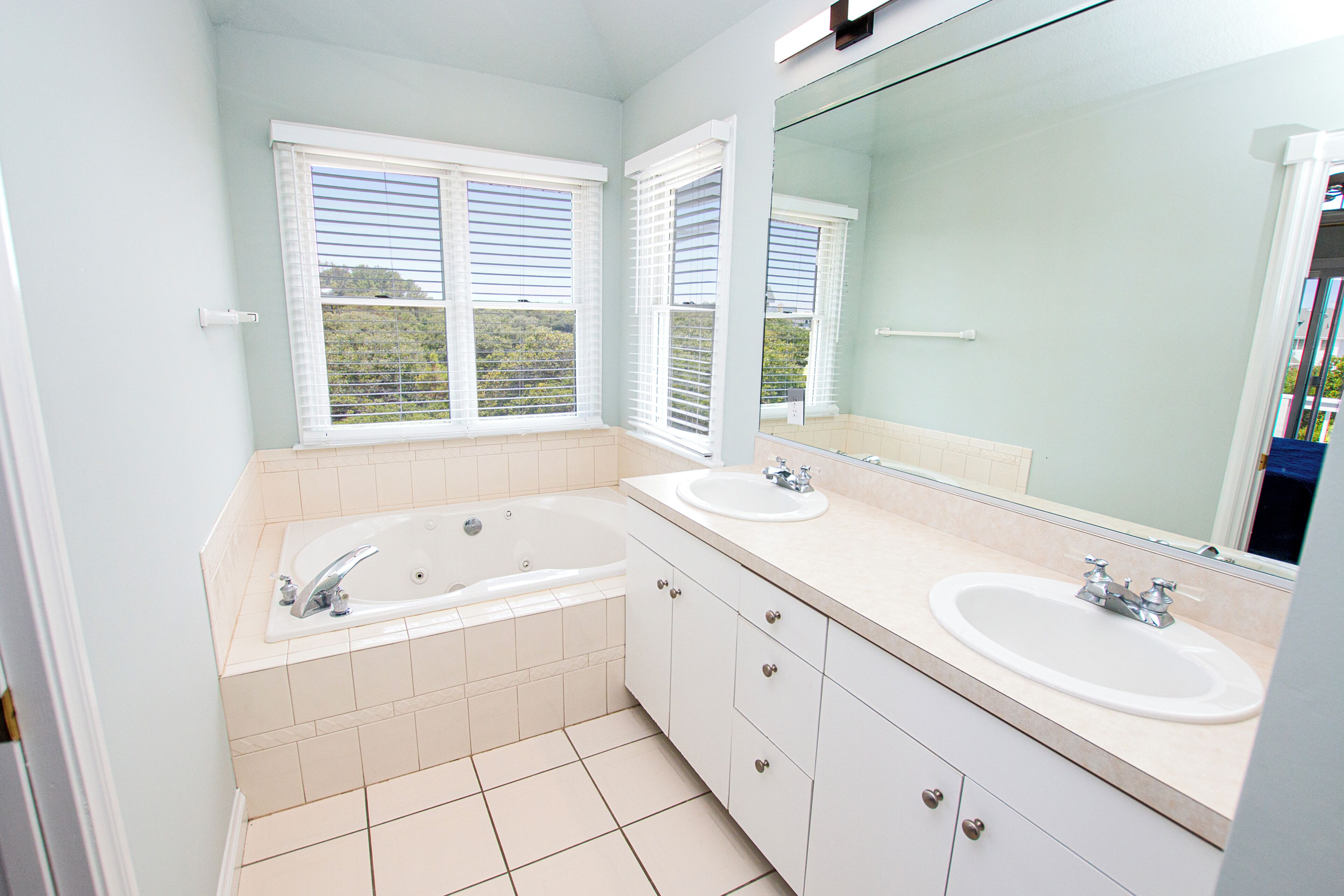 A bathroom with two sinks, a bathtub, and a large mirror.