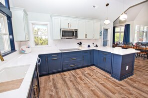 Een moderne keuken met witte kasten, een houten vloer en een groot eiland.