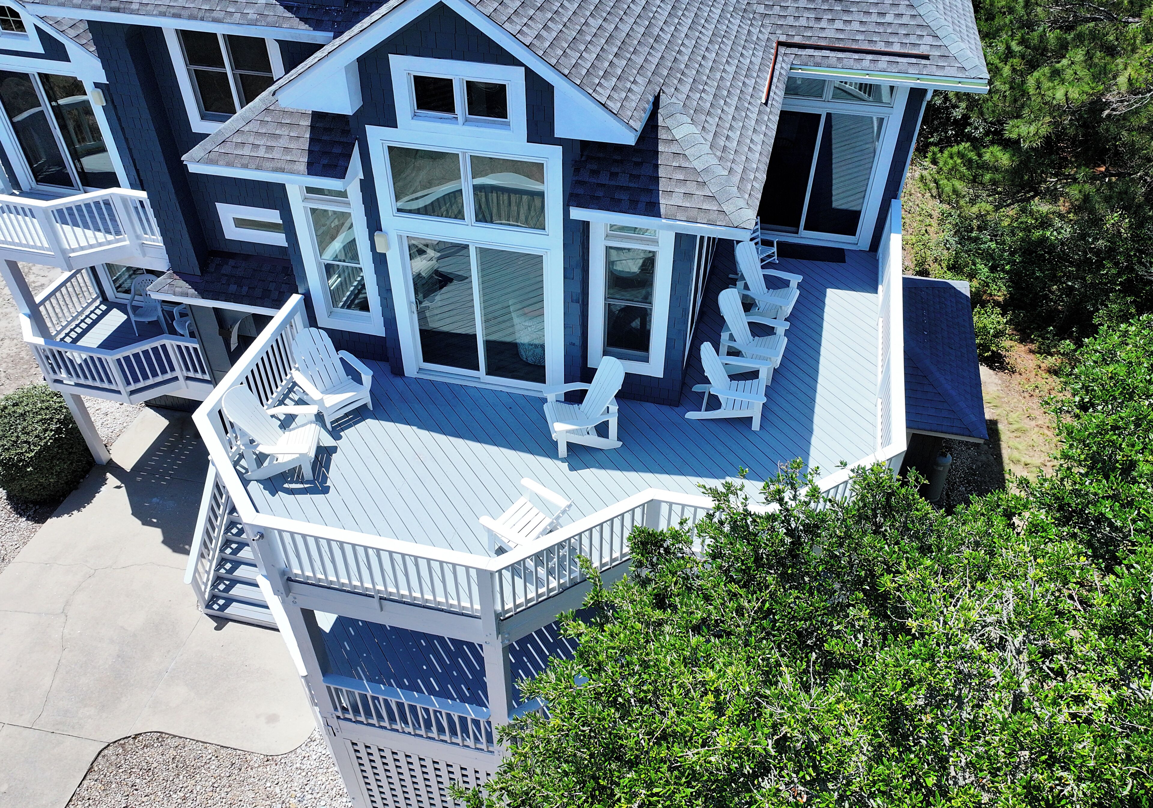 A multi-story house with a deck, multiple windows, and outdoor seating.