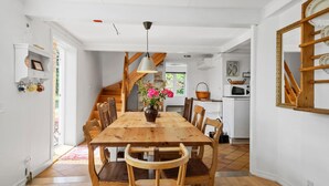 A dining area with a wooden table and chairs, a vase with flowers, and a staircase leading to another room. - Nice home in Svaneke with WiFi (Svaneke)
