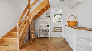 A kitchen with a wooden staircase, white cabinets, and a window with a view of greenery. - Nice home in Svaneke with WiFi (Svaneke)