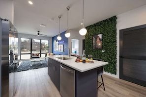 Een moderne keuken met een centraal eiland, een groene wand en uitzicht op de stad.