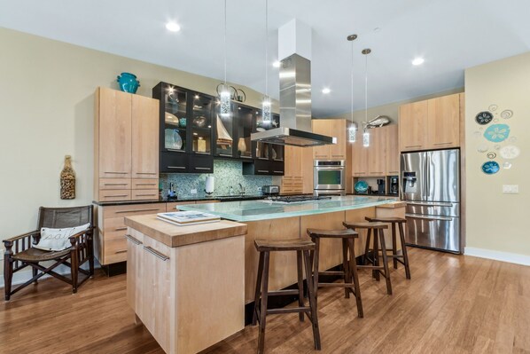 Una cocina moderna con una isla central, electrodomésticos de acero inoxidable y armarios de madera.