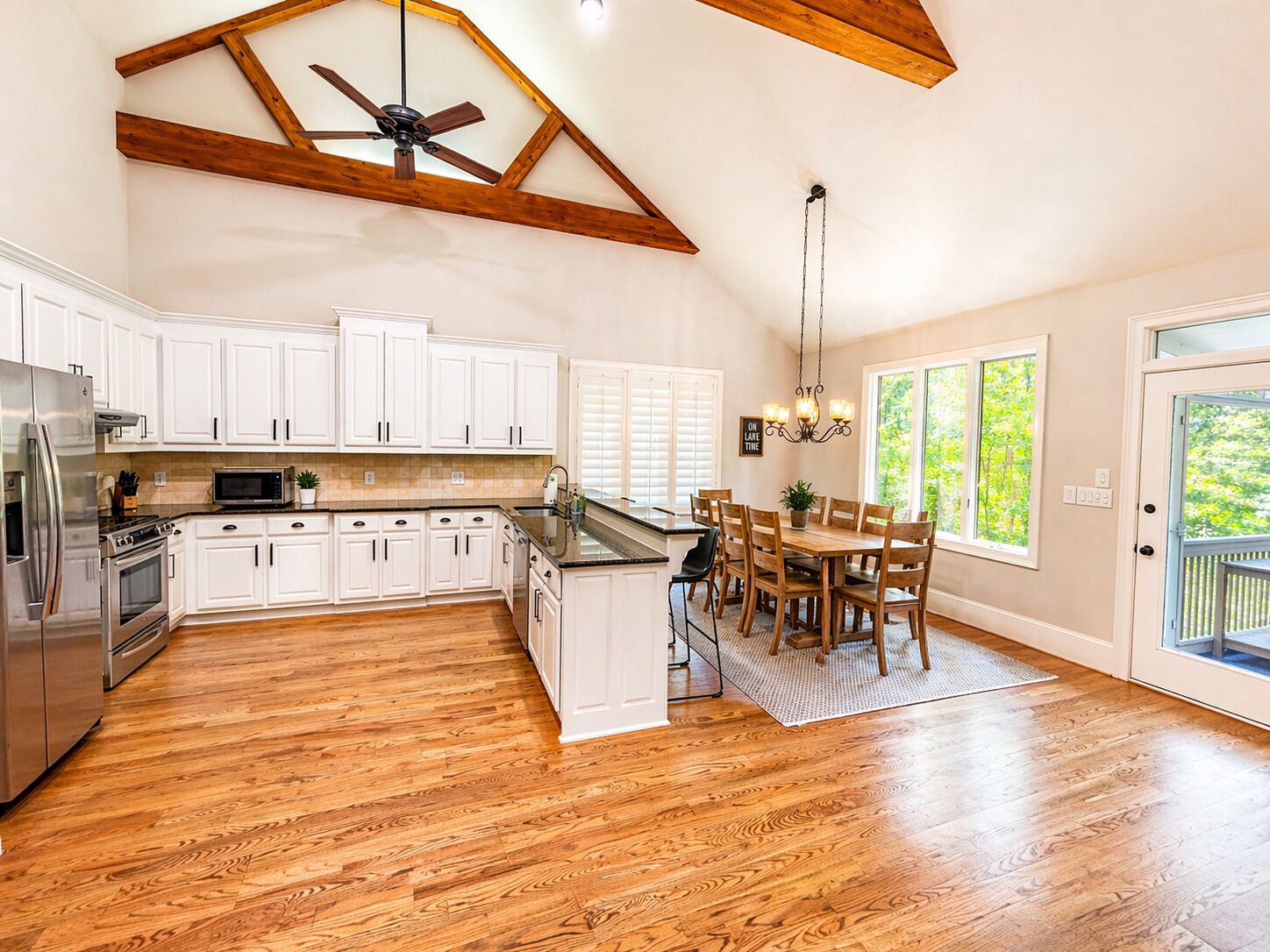 A spacious kitchen with white cabinets, a wooden ceiling, and a dining area with a table and chairs.