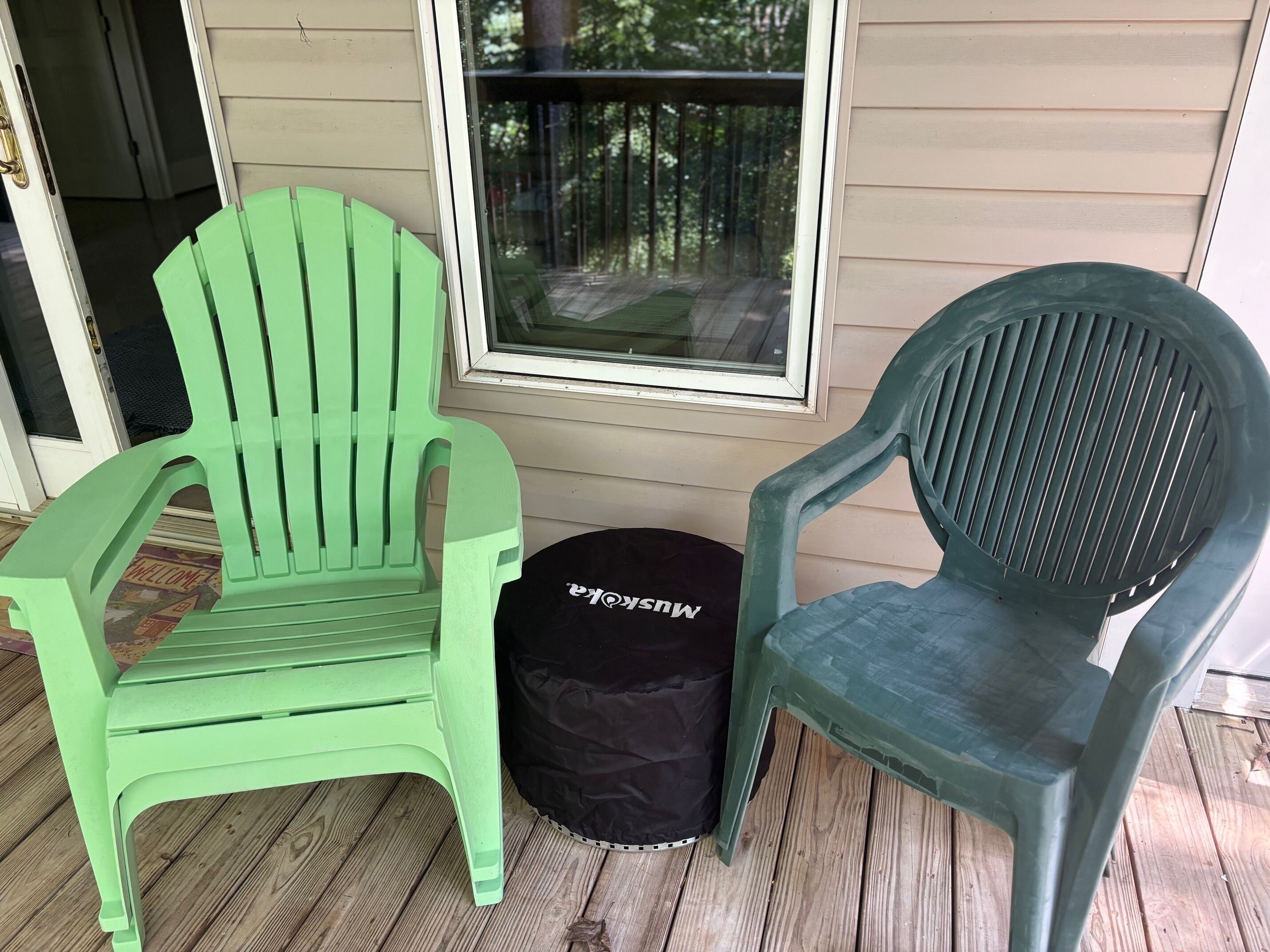 Deux chaises en plastique vertes et un sac noir sur une terrasse en bois.