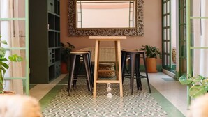 A room with a patterned floor, a wooden table with two stools, a large mirror on the wall, and green-framed windows. - Oliva I Modern 2 Bed Apart in Mexico City (Mexico City)