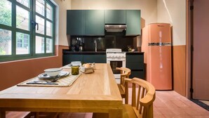 A modern kitchen with teal cabinets, a wooden dining table, and a pink refrigerator. - Oliva I Modern 2 Bed Apart in Mexico City (Mexico City)