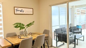 A dining area with a table and chairs, a potted plant, and a sliding glass door leading to an outdoor seating area. - Luxe & Modern Home-10 min to Disney Parks+Heated Pool+ Pets allowed (Kissimmee)