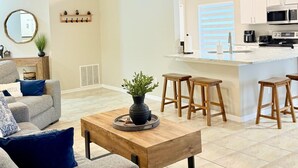 A modern living room with a grey sofa, a wooden coffee table, and a ceiling fan. - Luxe & Modern Home-10 min to Disney Parks+Heated Pool+ Pets allowed (Kissimmee)