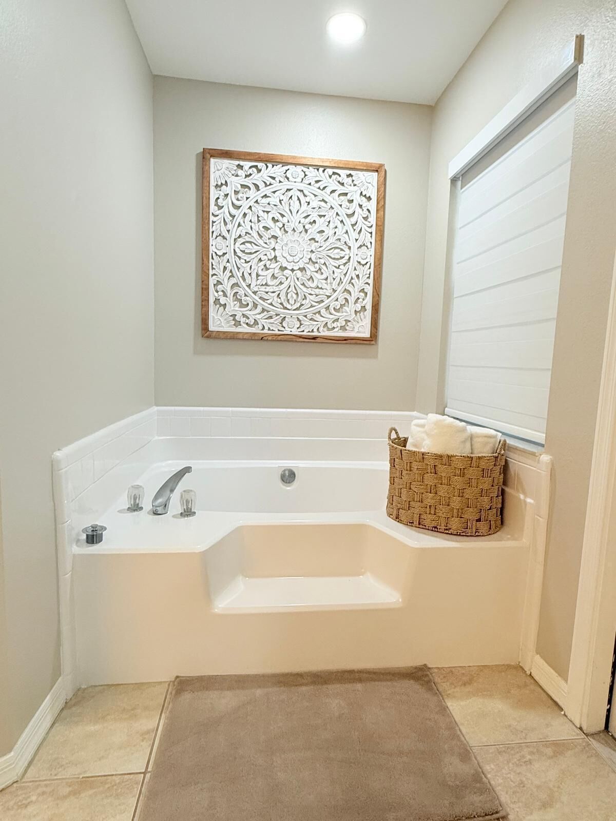 A bathroom with a freestanding bathtub, a decorative wall piece, and a wicker basket with towels.