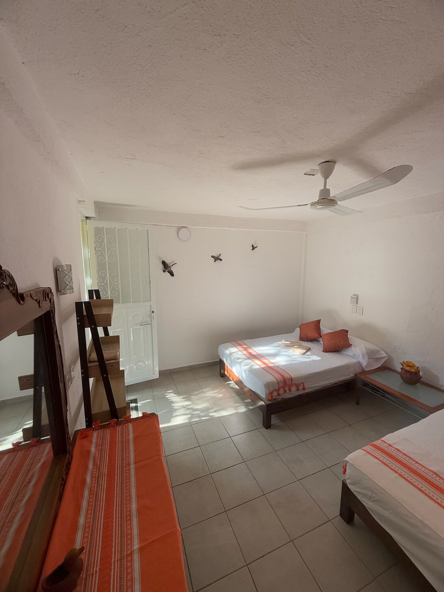Una camera da letto con un letto, una ventola da pavimento e una finestra con tende.