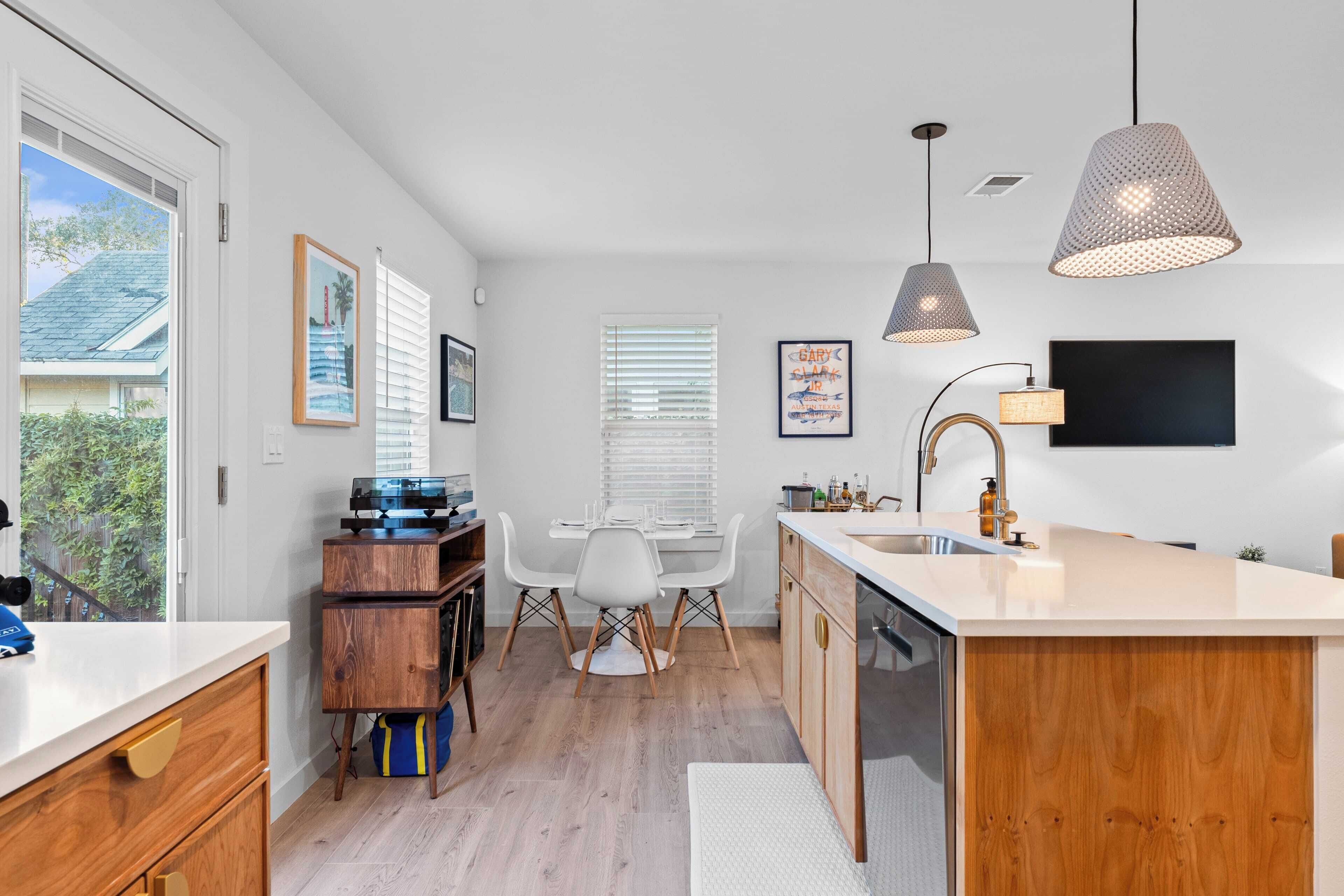 A modern kitchen with a central island, white cabinetry, and pendant lighting.