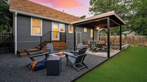 Un patio trasero con porche cubierto, mobiliario exterior, una chimenea y una terraza de madera.