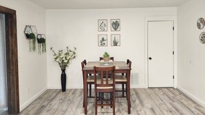 A dining area with a wooden table and chairs, a vase with flowers, and wall-mounted planters. - Spacious 4BR Home, Screened Porch, Fenced Yard, Pet-Friendly, 7 Min to Benning (Columbus)