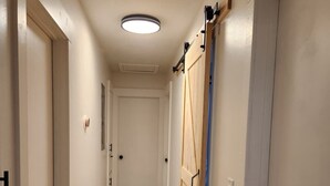 A hallway with wooden flooring, white walls, and a ceiling light. - Spacious 4BR Home, Screened Porch, Fenced Yard, Pet-Friendly, 7 Min to Benning (Columbus)
