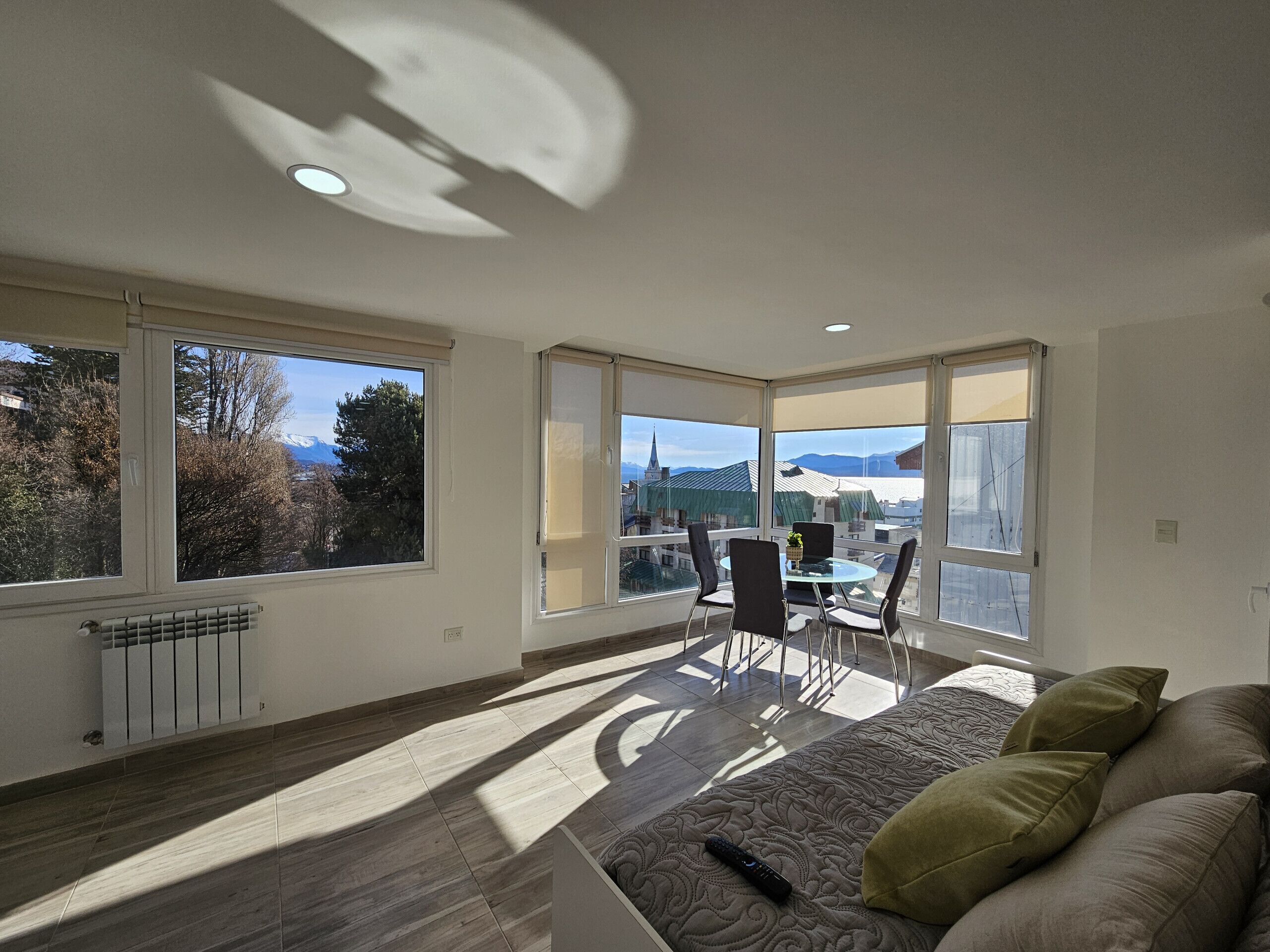 Ein geräumiges Zimmer mit großem Fenster, einem Essbereich und einer Couch.